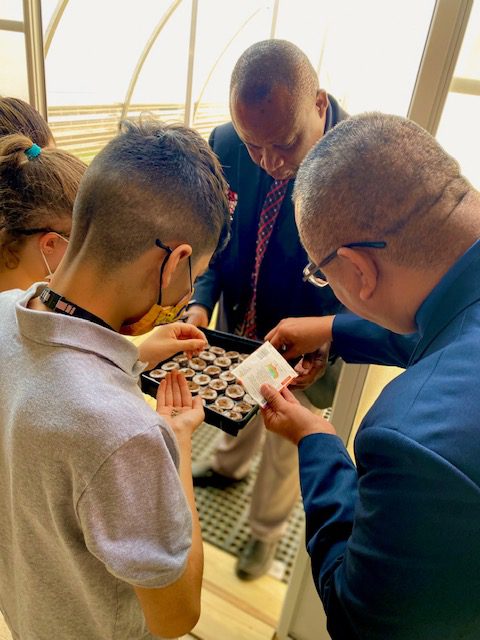 Students plant seeds with Superintendent Rolando Ramirez while Dr. Samuel Ebong assists. 