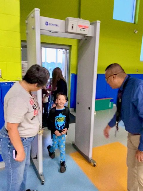 Menchaca Early Childhood Center Principal Mrs. Tanya Mares and Superintendent Rolando Ramirez guide a student through the metal detector.